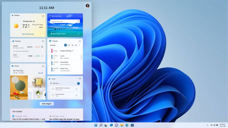Vysunutý panel widgetov na ľavej strane plochy Windows 11 s hodinami 11:11, dlaždicami Počasie, Microsoft Edge, Watchlist, Kalendár, Fotky a To Do, pod nimi sekcia Top stories; vpravo modrá vlnová tapeta.