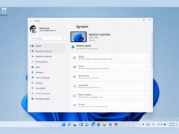 Okno Nastavení Windows 11 otvorené na stránke Systém, s bočnou ponukou položiek ako Bluetooth a zariadenia, Personalizácia či Windows Update a s dlaždicami Obrazovka, Zvuk a Oznámenia; pod oknom je panel úloh so zarovnanými ikonami v strede.