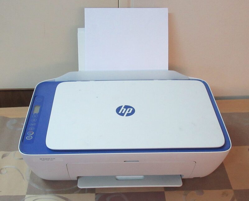 Biela multifunkčná atramentová tlačiareň HP DeskJet s modrým rámom a papierom v zásobníku